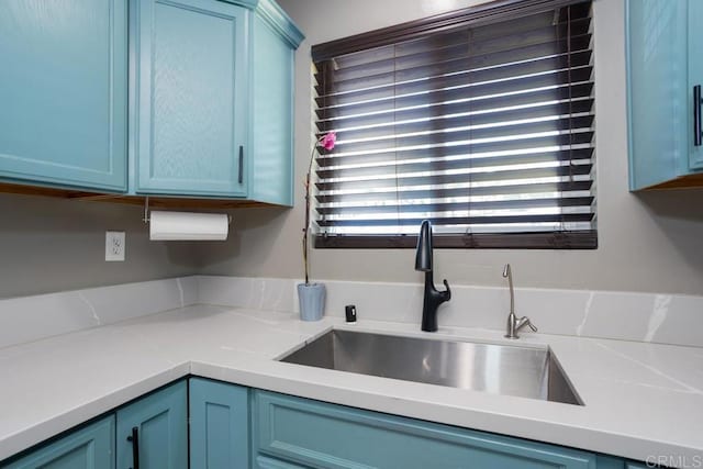 kitchen featuring a sink, blue cabinetry, and light countertops