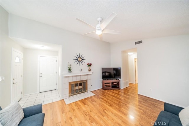 3628 Grizzley Creek Ct, Ontario, CA 91761 - living room featuring light wood-type flooring, ceiling fan, a tiled fireplace, and baseboards