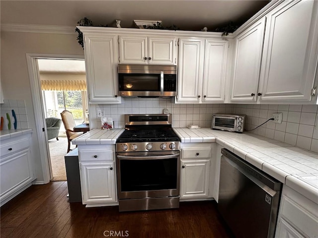 19628 Pine Valley Ave, Porter Ranch, CA 91326 - kitchen with stainless steel appliances, tile counters, white cabinets, and crown molding