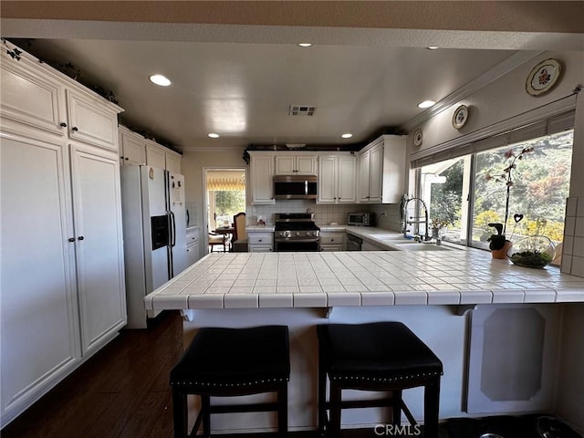 19628 Pine Valley Ave, Porter Ranch, CA 91326 - kitchen featuring stainless steel appliances, a sink, ornamental molding, tile countertops, and a peninsula