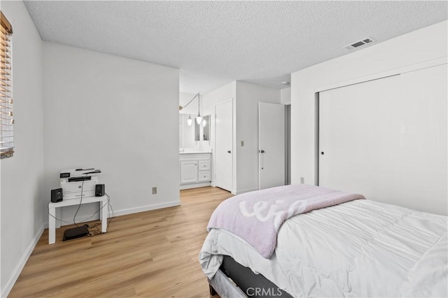 2210 El Rancho Cir, Hemet, CA 92545 - bedroom with light wood-style flooring, a textured ceiling, baseboards, a closet, and ensuite bath