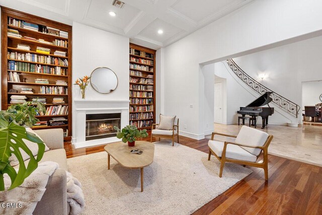 12986 Macdonald Dr, Ojai, CA 93023 - living room with built in shelves, a glass covered fireplace, beam ceiling, coffered ceiling, and wood finished floors