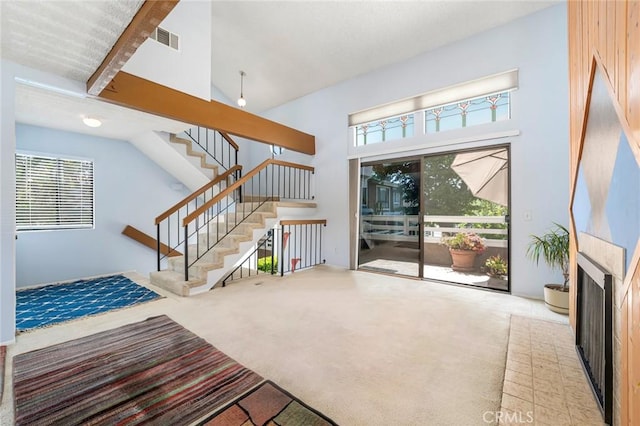 917 W Imperial Unit 64, La Habra, CA 90631 - unfurnished living room with high vaulted ceiling, stairway, carpet, a fireplace, and beamed ceiling