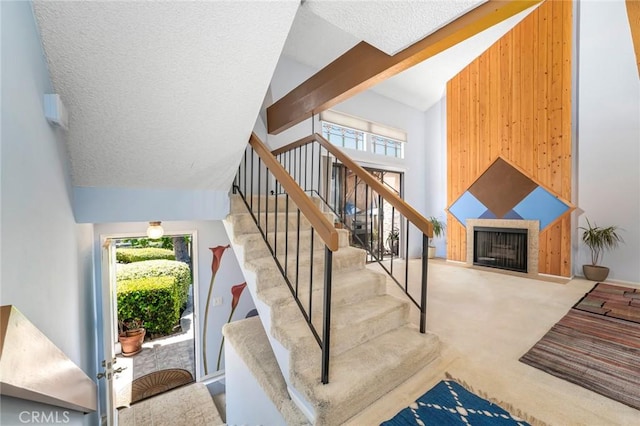 917 W Imperial Unit 64, La Habra, CA 90631 - stairway with carpet floors, wooden walls, a fireplace, a textured ceiling, and high vaulted ceiling