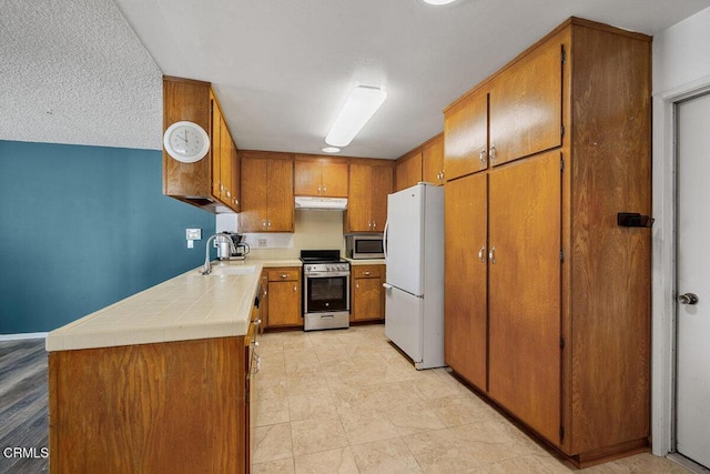 203 E Garden Grn, Port Hueneme, CA 93041 - kitchen featuring appliances with stainless steel finishes, brown cabinets, under cabinet range hood, a sink, and tile counters