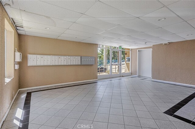 10290 Tujunga Canyon Blvd Unit 102, Tujunga, CA 91402 - unfurnished room featuring baseboards, tile patterned flooring, mail area, and a paneled ceiling