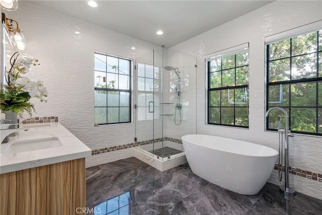 bathroom with marble tiled flooring, a shower stall, a soaking tub, recessed lighting, and tile walls