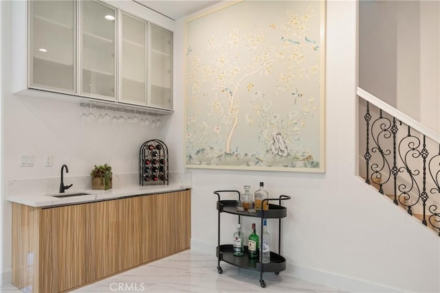 indoor wet bar with light marble finish flooring and baseboards
