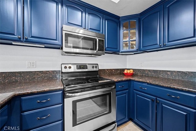 3936 W 5th St Unit 44, Santa Ana, CA 92703 - kitchen featuring appliances with stainless steel finishes, blue cabinetry, dark countertops, and glass insert cabinets