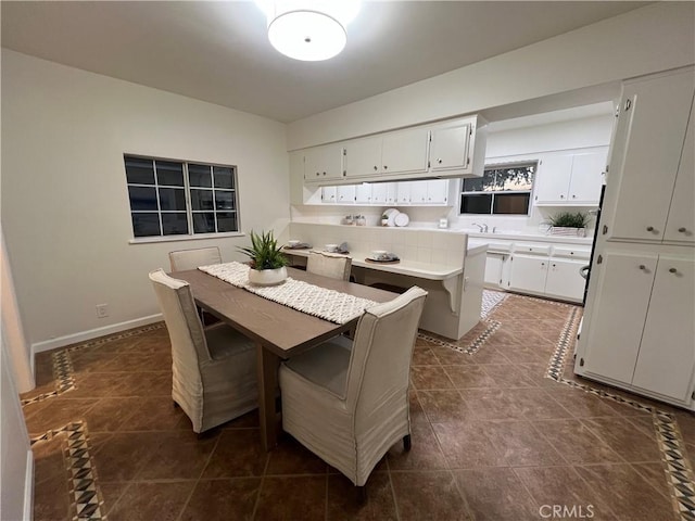 dining room with dark tile patterned floors and baseboards