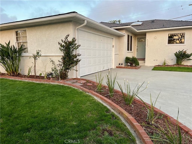 view of front of house with stucco siding, a garage, concrete driveway, and a front yard
