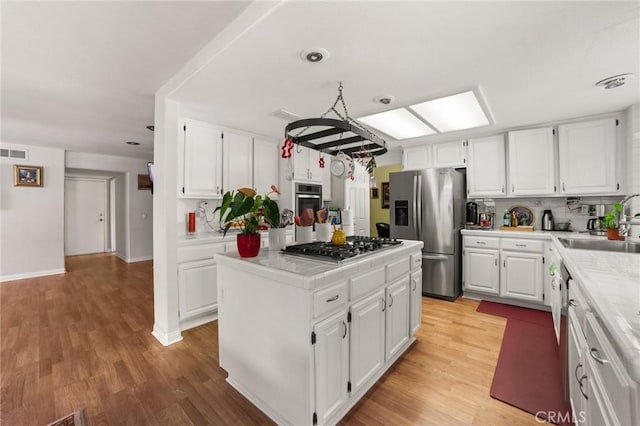 23838 Spring Branch Ct, Murrieta, CA 92562 - kitchen with stainless steel appliances, a sink, white cabinetry, light wood-type flooring, and a kitchen island