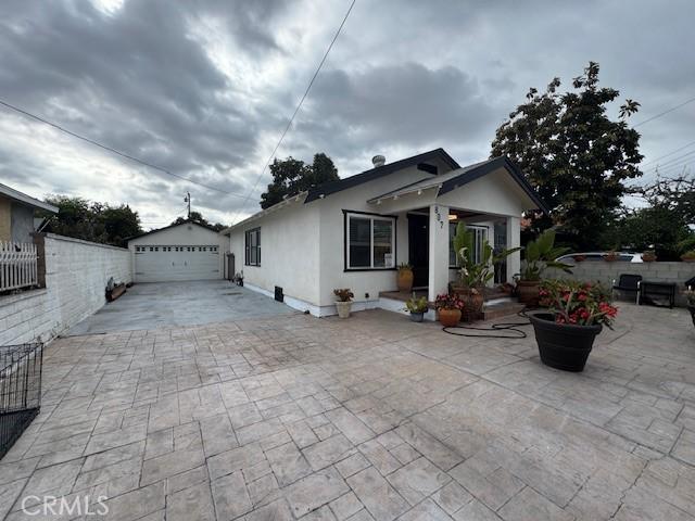 807 N Pearl Ave, Compton, CA 90221 - view of front of house featuring a detached garage, an outdoor structure, stucco siding, and fence