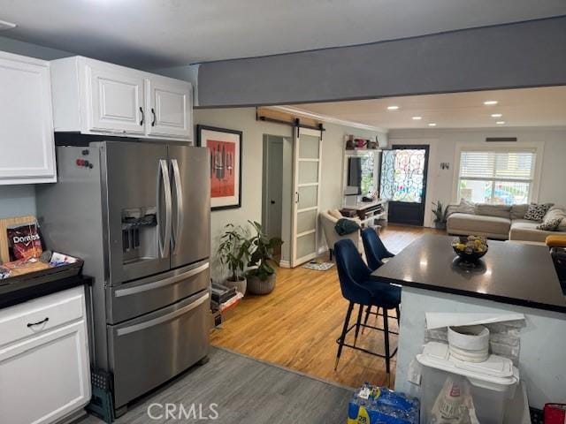 807 N Pearl Ave, Compton, CA 90221 - kitchen featuring stainless steel fridge, a barn door, light wood-style flooring, white cabinetry, and open floor plan