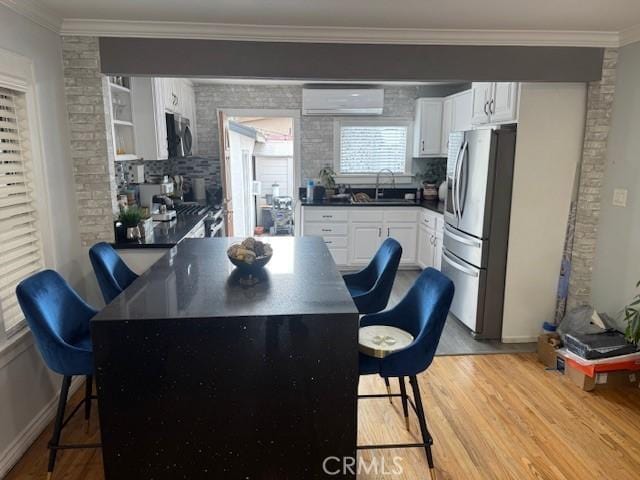 807 N Pearl Ave, Compton, CA 90221 - kitchen featuring appliances with stainless steel finishes, a breakfast bar area, a sink, dark countertops, and a wall unit AC