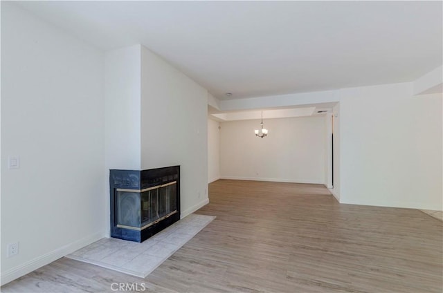 4200 Via Arbolada Unit 123, Los Angeles, CA 90042 - unfurnished living room featuring wood finished floors, a chandelier, a multi sided fireplace, and baseboards