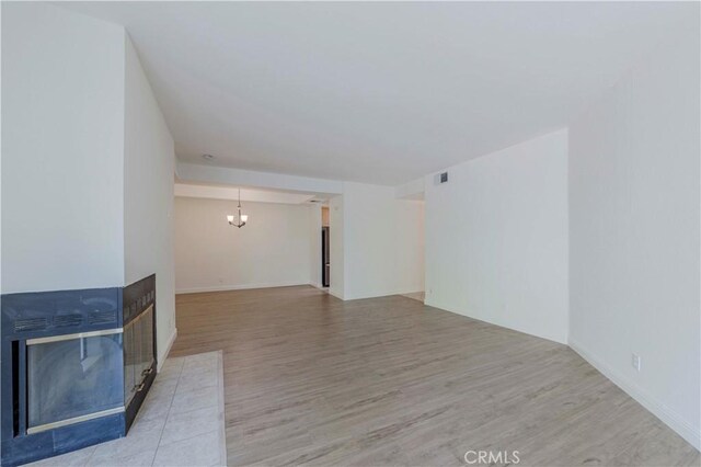 4200 Via Arbolada Unit 123, Los Angeles, CA 90042 - unfurnished living room featuring a multi sided fireplace, wood finished floors, and a chandelier