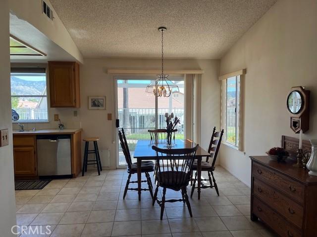 3060 Summer Set Cir, Banning, CA 92220 - dining room featuring a textured ceiling, a chandelier, plenty of natural light, and light tile patterned floors