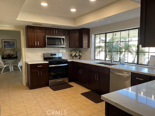 3060 Summer Set Cir, Banning, CA 92220 - kitchen featuring stainless steel appliances, a sink, a tray ceiling, light countertops, and recessed lighting
