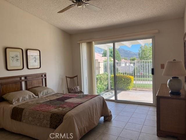 3060 Summer Set Cir, Banning, CA 92220 - bedroom with a textured ceiling, access to exterior, light tile patterned floors, a mountain view, and a ceiling fan