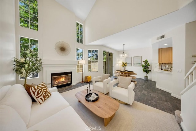 13385 Savanna, Tustin, CA 92782 - living room featuring dark wood-style floors, a glass covered fireplace, baseboards, a chandelier, and a towering ceiling