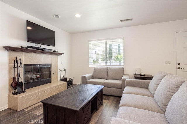 living area with dark wood-style flooring, a tiled fireplace, and recessed lighting