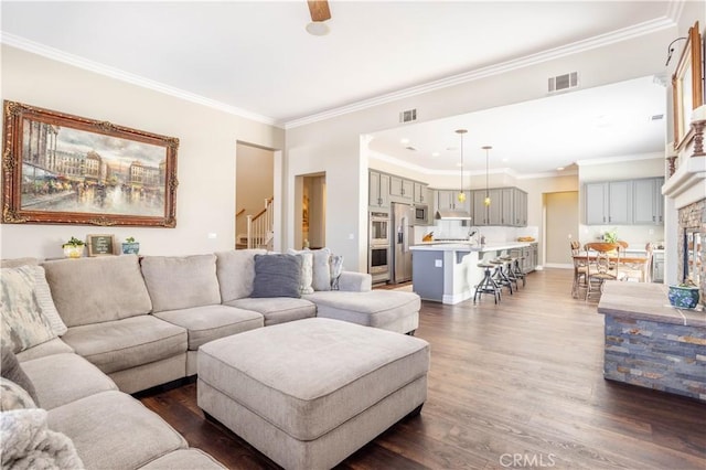 living room with dark wood-type flooring, crown molding, stairs, and baseboards