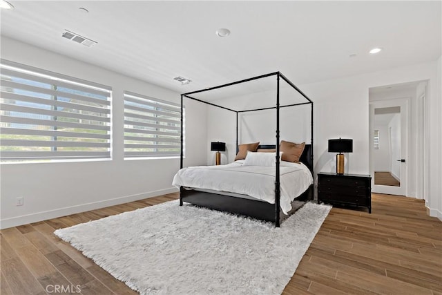 bedroom with baseboards, wood finished floors, and recessed lighting