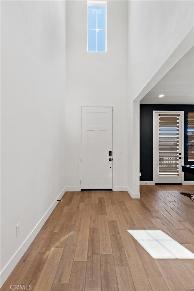 foyer entrance with hardwood / wood-style flooring, a high ceiling, and baseboards
