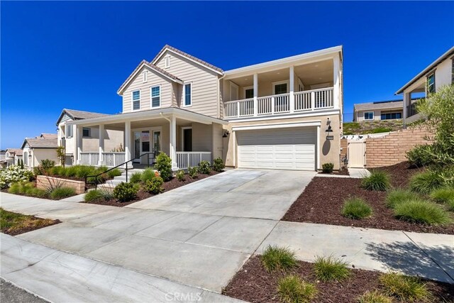 view of front facade with covered porch, a garage, concrete driveway, a gate, and a balcony