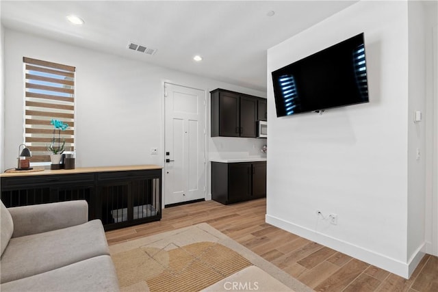 living area with light wood-style flooring, baseboards, and recessed lighting