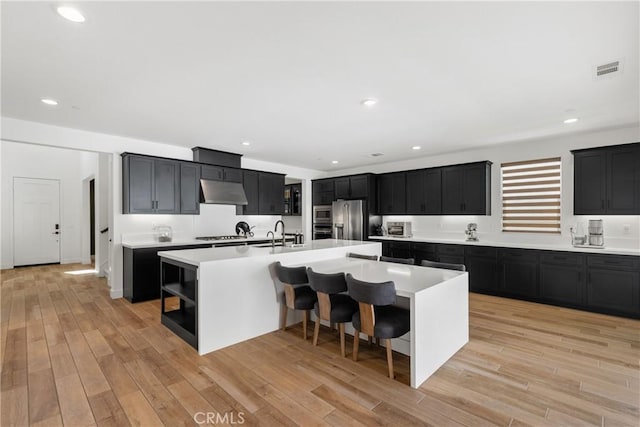 kitchen featuring stainless steel appliances, light countertops, under cabinet range hood, dark cabinets, and recessed lighting