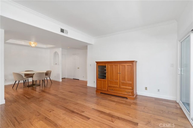 living area with light wood-type flooring, ornamental molding, baseboards, and arched walkways