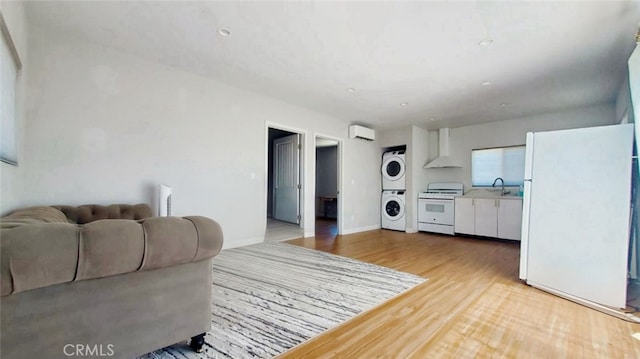 606608 Fairview Ave, Los Angeles, CA 90033 - living room with stacked washing machine and dryer, light wood-style floors, a wall mounted air conditioner, and baseboards