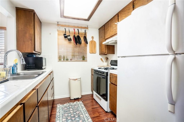 321 13th St, Huntington Beach, CA 92648 - kitchen featuring white appliances, under cabinet range hood, a sink, tile counters, and dark wood-style flooring