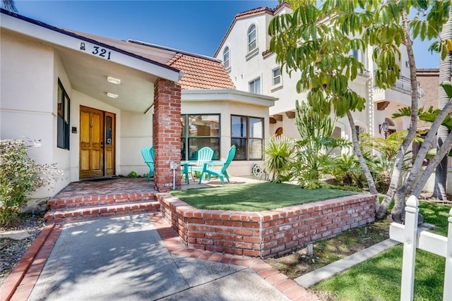 321 13th St, Huntington Beach, CA 92648 - property entrance featuring stucco siding, a tiled roof, and a lawn