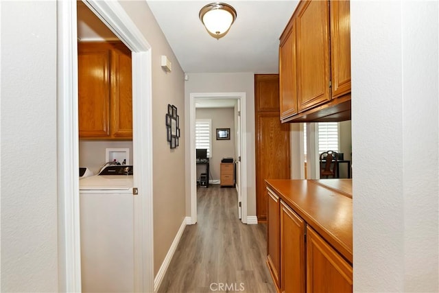 hall featuring washer / clothes dryer, light wood-style floors, and baseboards