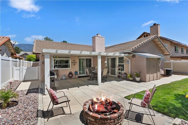 back of house with an outdoor fire pit, a chimney, a fenced backyard, a patio area, and a tiled roof