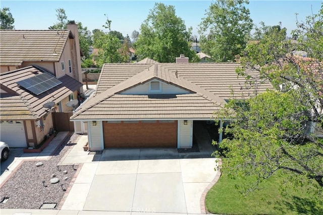 view of front of home with a tile roof, driveway, a chimney, and an attached garage