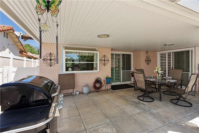 view of patio featuring area for grilling, fence, and outdoor dining space