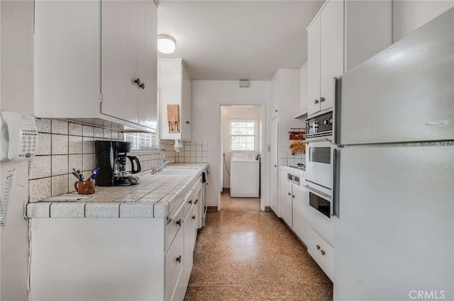 404 N San Jose Ave, Covina, CA 91723 - kitchen featuring white appliances, washer / clothes dryer, decorative backsplash, and white cabinets