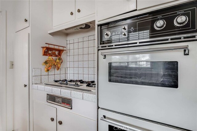 404 N San Jose Ave, Covina, CA 91723 - kitchen with white cabinetry, backsplash, under cabinet range hood, stovetop, and tile counters