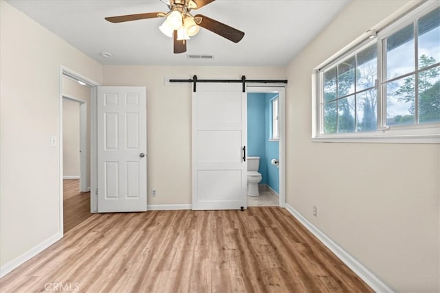 3439 De Anza Ave, Merced, CA 95348 - unfurnished bedroom featuring light wood-style flooring, baseboards, and a barn door