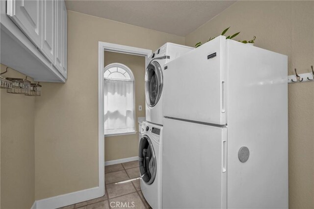 21425 Valley Oak Dr, Middletown, CA 95461 - laundry room with stacked washer and clothes dryer, cabinet space, light tile patterned floors, and baseboards