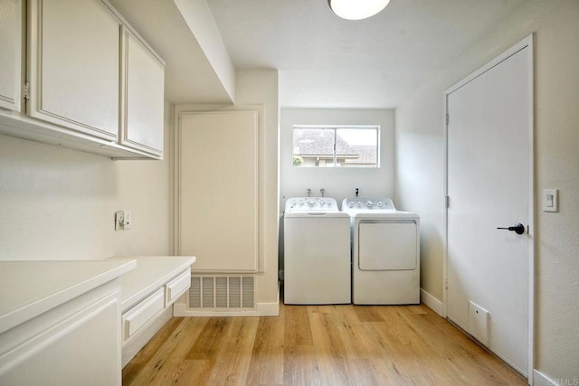 washroom featuring washer and clothes dryer, light wood-style flooring, and cabinet space