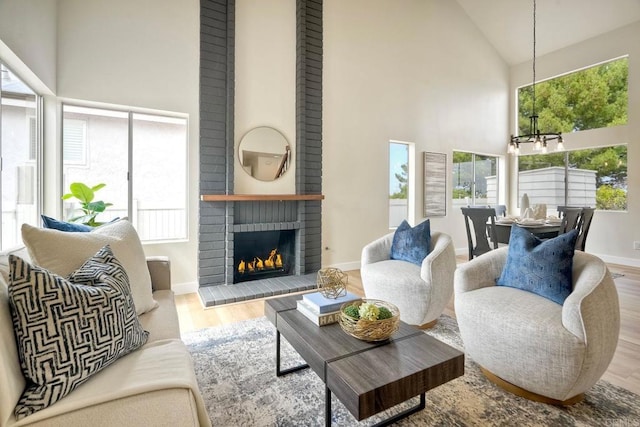 living room featuring high vaulted ceiling, a chandelier, plenty of natural light, and wood finished floors