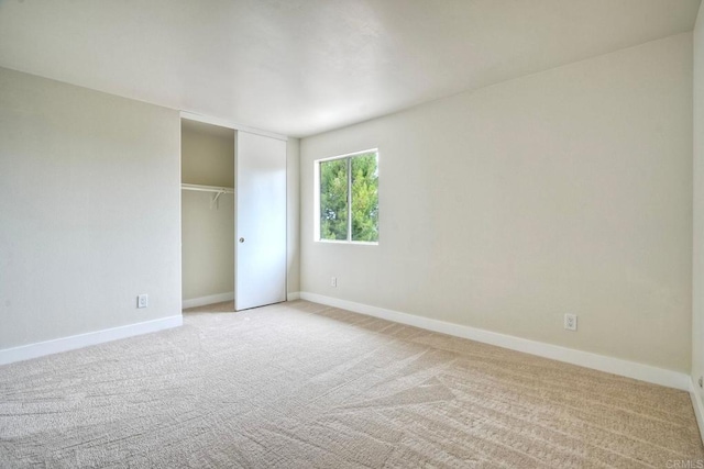 unfurnished bedroom with light carpet, baseboards, and a closet