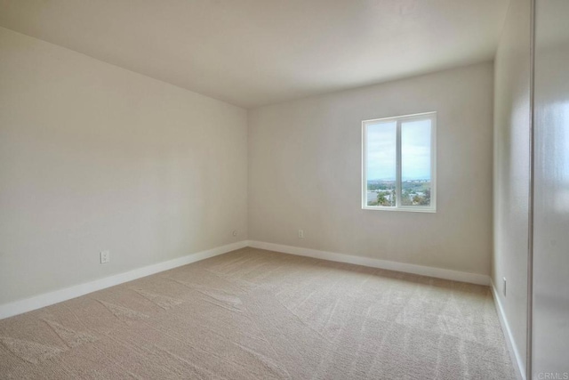 unfurnished room with light colored carpet and baseboards