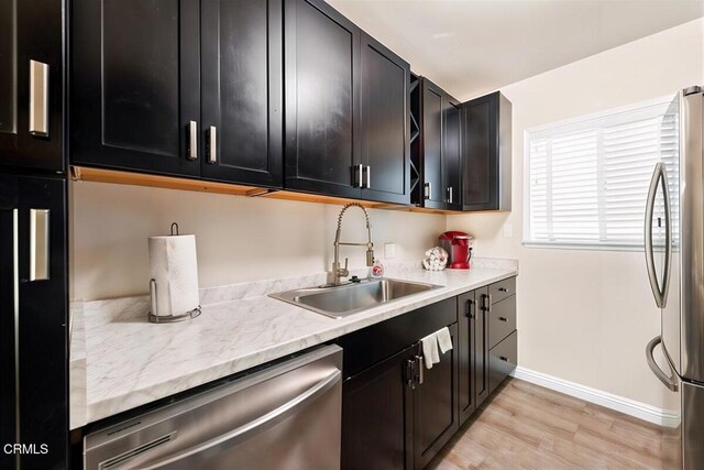 256 Melrose Dr, Oxnard, CA 93035 - kitchen featuring appliances with stainless steel finishes, a sink, baseboards, dark cabinetry, and light wood-type flooring