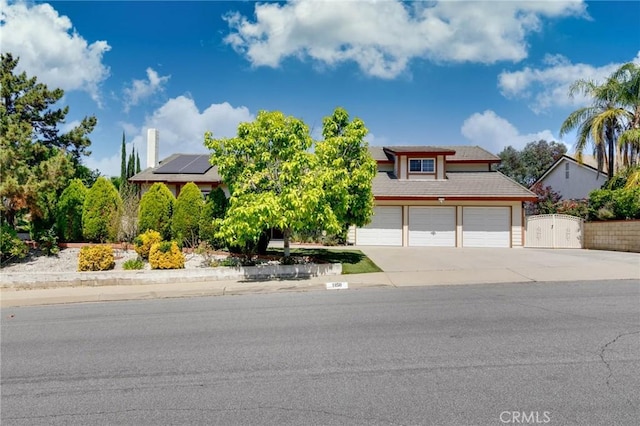 1158 Regal Canyon Dr, Walnut, CA 91789 - view of property hidden behind natural elements with roof mounted solar panels, concrete driveway, a gate, a garage, and fence